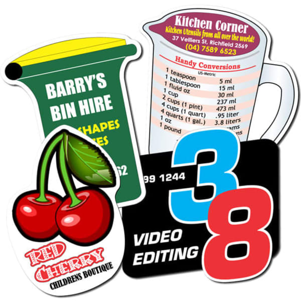 Custom-shaped fridge magnets in various colours, featuring a cherry, measuring jug, and business card designs, with logos.