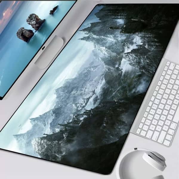 A large dark green and grey gaming mat featuring a mountainous landscape, positioned on a desk with a keyboard and mouse.