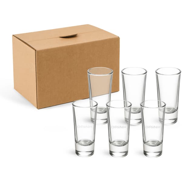 A set of six clear glass shot glasses beside a cardboard box. The glasses are tall and slender.