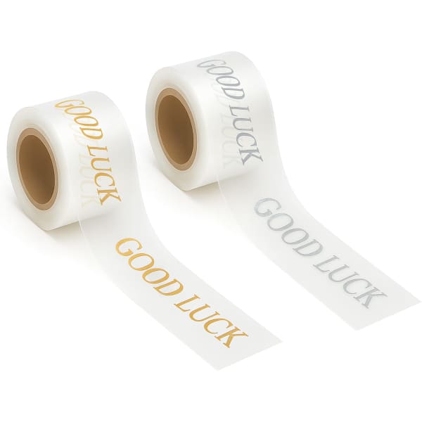 Two rolls of promotional soft ribbon in white, featuring "Good Luck" printed in gold and silver text.