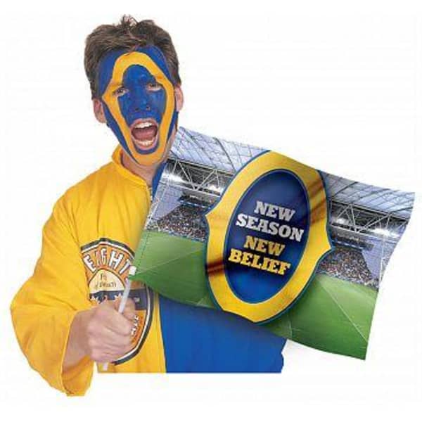 A person dressed in a bright yellow and blue outfit, with face paint in the same colours, holds a large flag.
