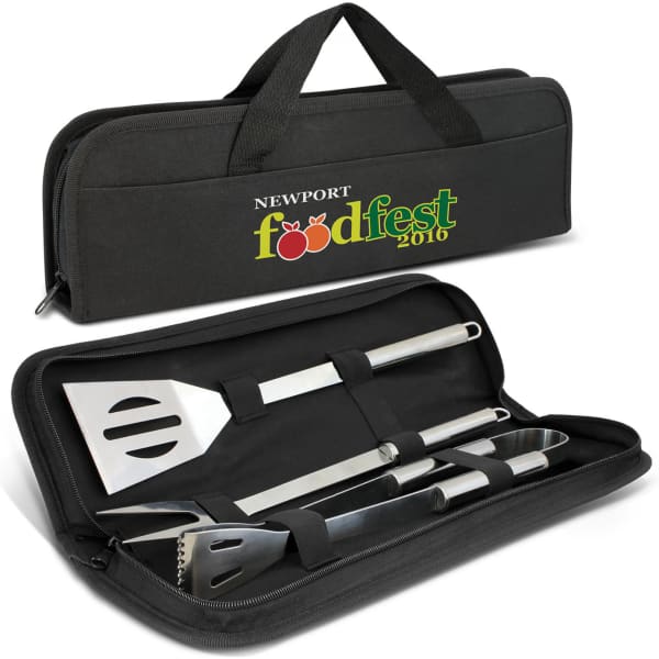 A black carrying case with a handle contains a stainless steel spatula, tongs, and a fork. Features a logo.