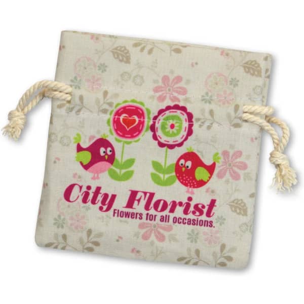 A small cotton gift bag in beige with floral patterns and a logo featuring colourful birds and flowers.
