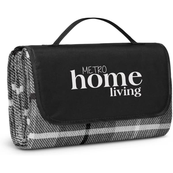A folded picnic blanket in black and grey, featuring a carry handle and a logo on the front.