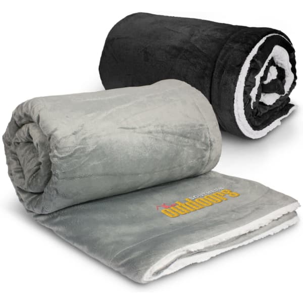 A grey and black luxury blanket, rolled and stacked, featuring a logo on the grey blanket.