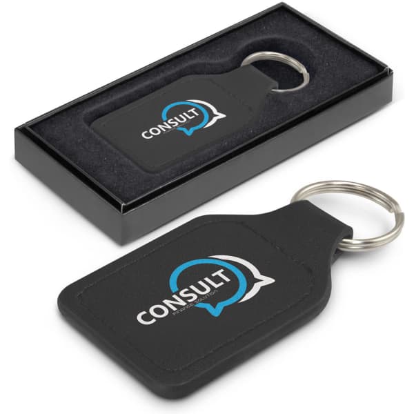 A square black leather key ring in a box, featuring a round metal key chain and a logo design.