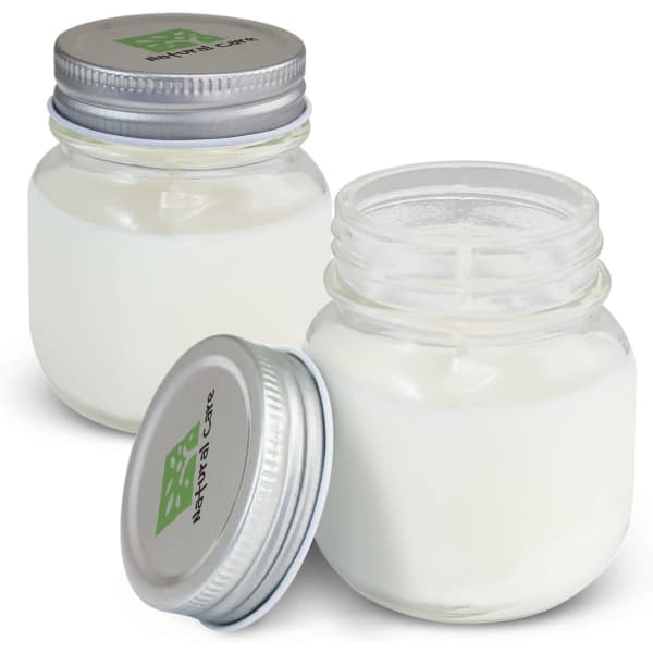 Two glass jars of a white scented candle, each with a silver metal lid and a brand logo on the top.