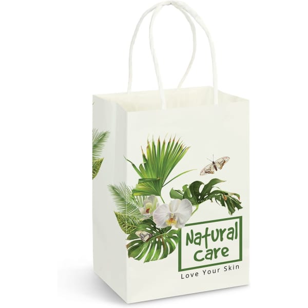 A small white paper carry bag featuring tropical leaves, flowers, and a logo. The bag has white handles.