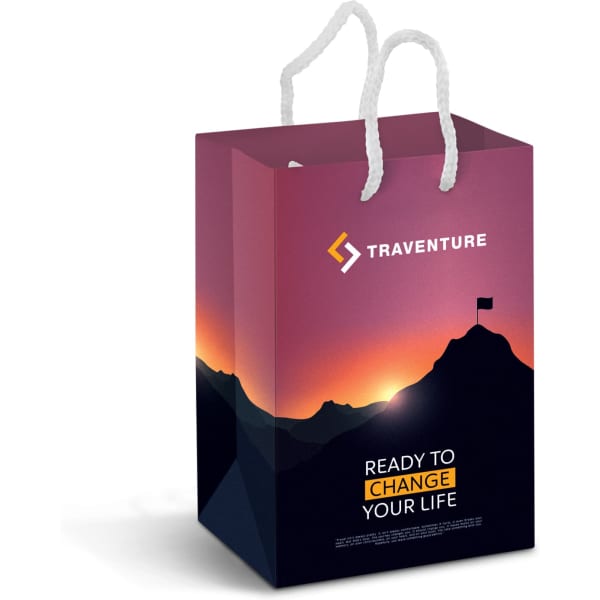 A small laminated paper carry bag in deep purple and black, featuring a logo and scenic mountain design with white handles.