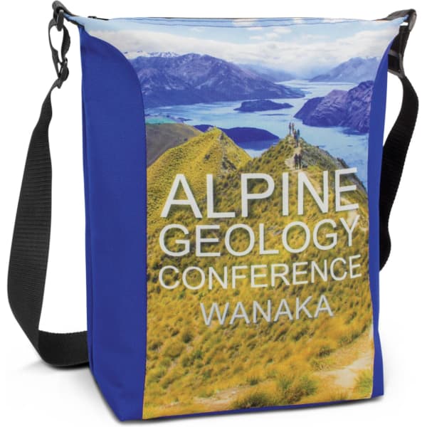 A conference cooler bag in blue with a scenic landscape print featuring mountains and lakes. It has an adjustable strap.
