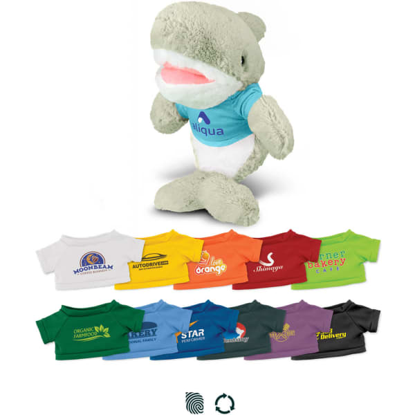 A soft, grey and white shark plush toy wearing a blue shirt, surrounded by various colourful t-shirts in different shades.