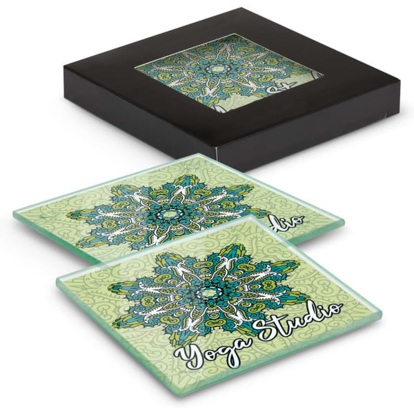 A set of two square glass coasters in green with intricate patterns, contained in a black box.