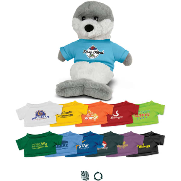 A grey and white seal plush toy wearing a blue t-shirt, surrounded by various small t-shirts in multiple colours.