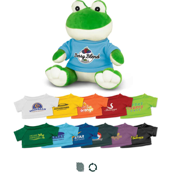 A green frog plush toy wearing a blue shirt, surrounded by various T-shirts in different colours and designs.