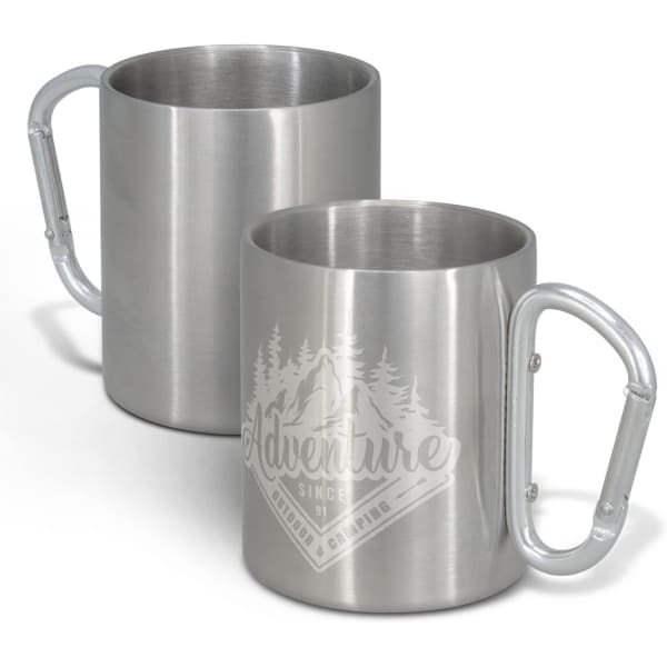 A metal coffee mug featuring a carabiner handle, with a design of mountains and trees. It has a metallic finish.