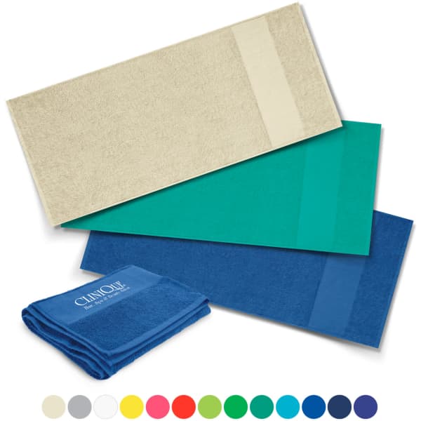 A set of bath towels in various colours: cream, teal, and dark blue, with one towel featuring a logo.