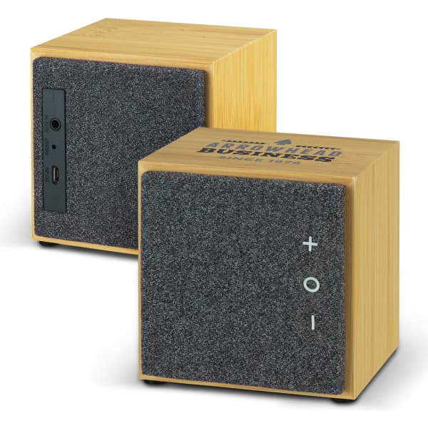 A square Bluetooth speaker with a bamboo body and grey fabric front, featuring control buttons and a logo on one side.