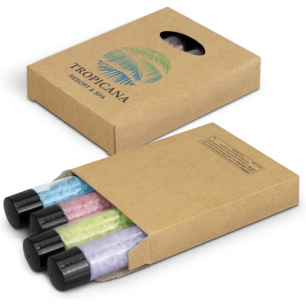 A set of three bath salt tubes in pink, green, and blue, packed in a brown cardboard box with branding.