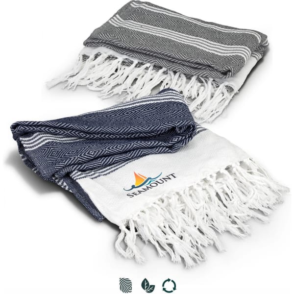 A folded throw blanket in navy and grey with fringe edges, featuring a logo on the white section.
