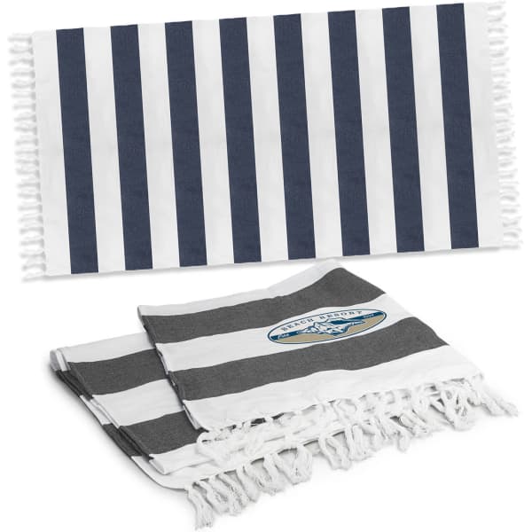 A striped cotton towel in navy blue and white, with a smaller grey and white striped towel underneath. Both towels have tassels and feature a logo.