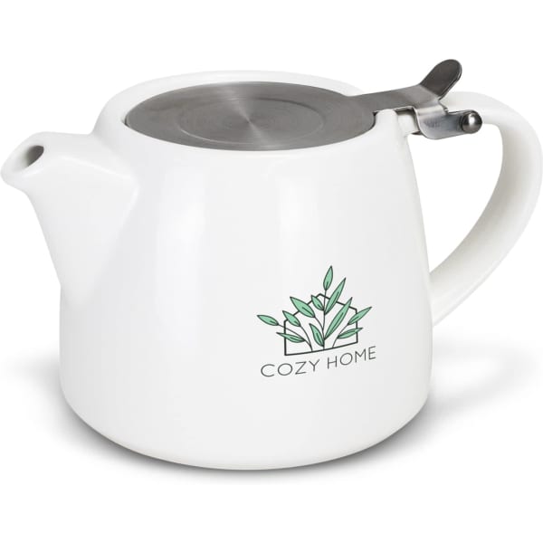 A white teapot with a metal lid and a logo featuring green leaves. Suitable for serving chai tea.