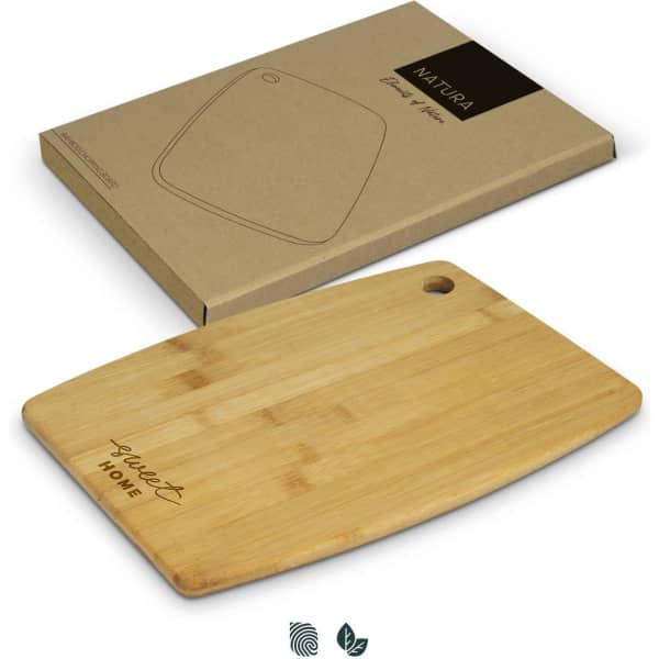 A bamboo chopping board with a rounded edge and a hole, placed beside its eco-friendly packaging.