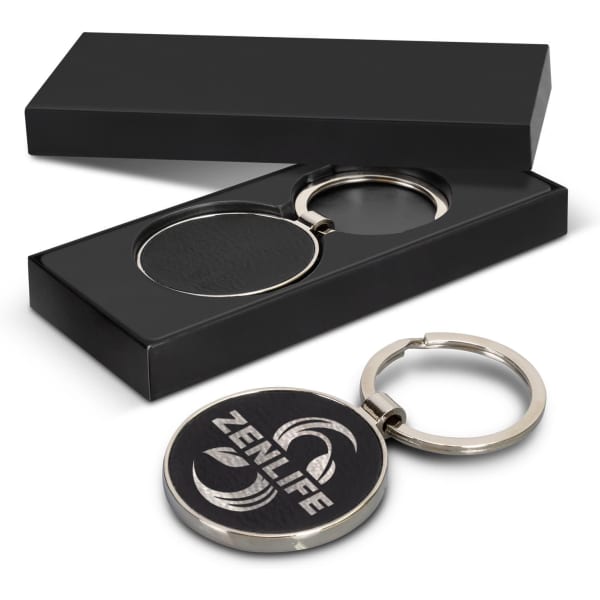A round silver key ring with a leather centre, presented in a sleek black gift box.