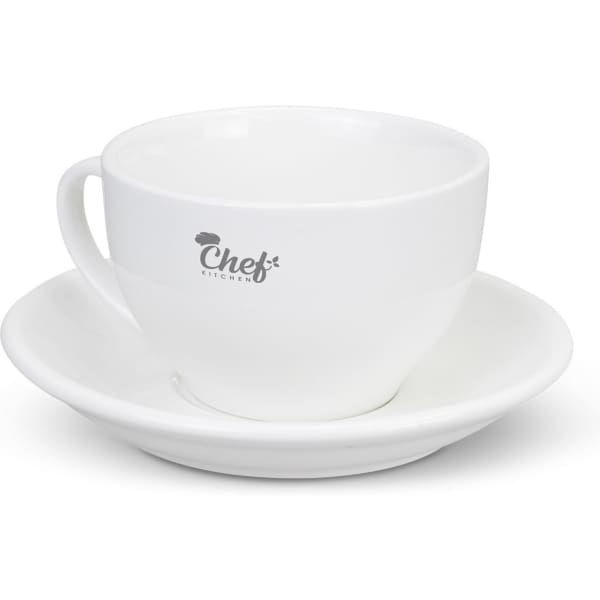 A white chai cup with a matching saucer, featuring a logo on the cup.
