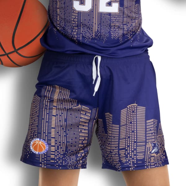 Custom women's basketball shorts in navy with a city skyline pattern and a logo. A basketball is being held.
