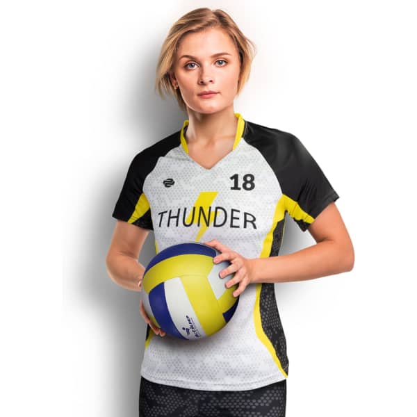 A woman in a black and yellow custom volleyball top holding a volleyball. The top features a logo and a sporty design.
