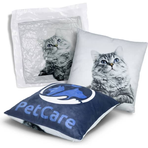 A plush cushion featuring a cat design, primarily in grey and white, packaged in a clear plastic bag with a logo.