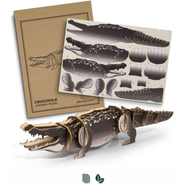 A wooden model of a crocodile in natural and dark brown hues, accompanied by a cardboard backing with design templates.