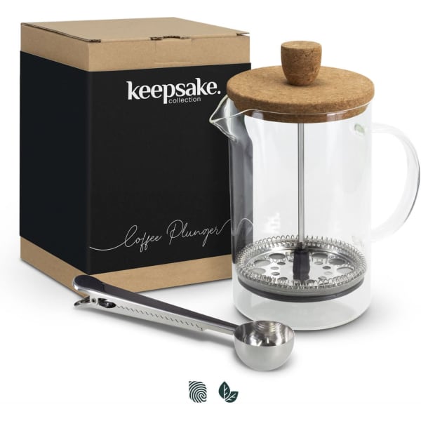 A coffee plunger with a glass body, cork lid, metal filter, and a matching coffee scoop in a boxed package.