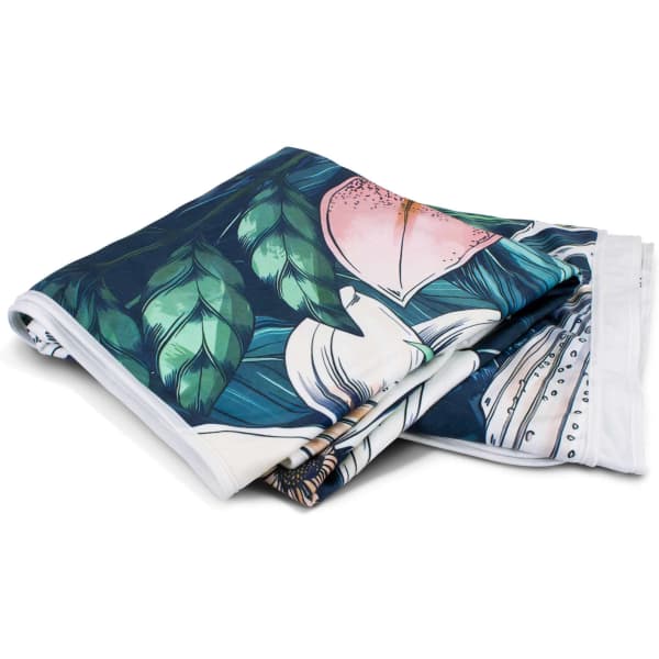 A vibrant, full-colour blanket featuring tropical leaves and flowers, folded neatly. The blanket has a white border.