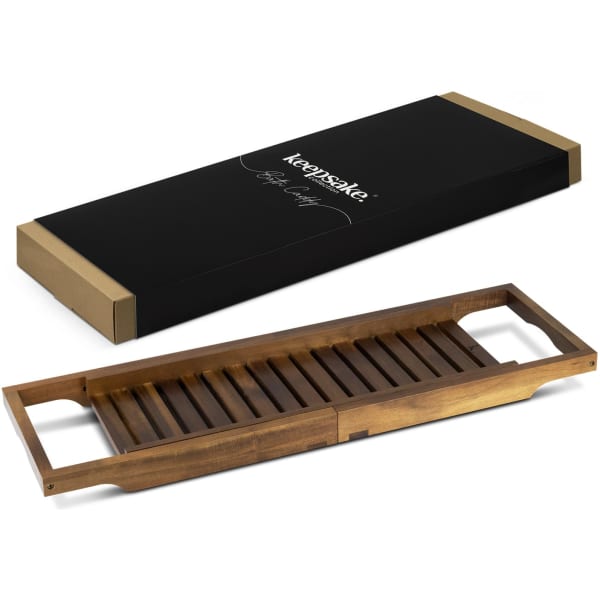 A wooden bath caddy in a warm brown finish, alongside its elegant black packaging with a logo.
