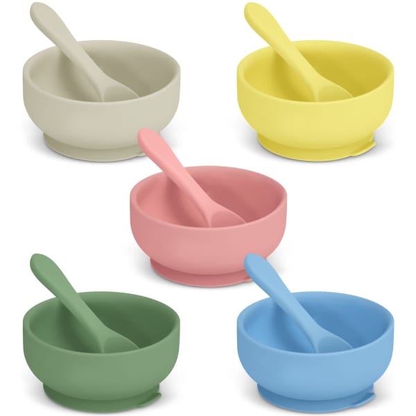 A set of five suction bowls in green, pink, yellow, grey, and blue, each with a matching spoon and a logo.