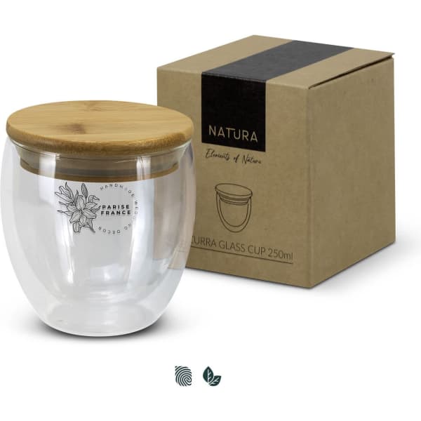 A glass cup with a bamboo lid, featuring a design on the front, beside its cardboard packaging.