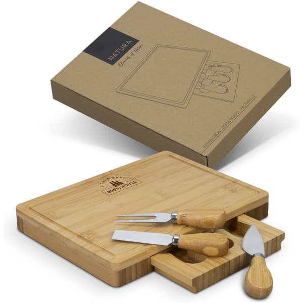A rectangular bamboo cheese board with three stainless steel knives, displayed in a brown box.