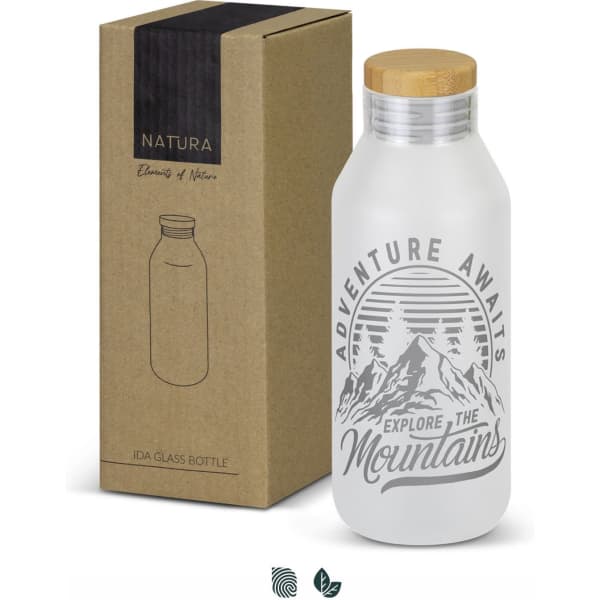 A drink bottle with a frosted glass body, wooden lid, and a mountain graphic, presented alongside its packaging.