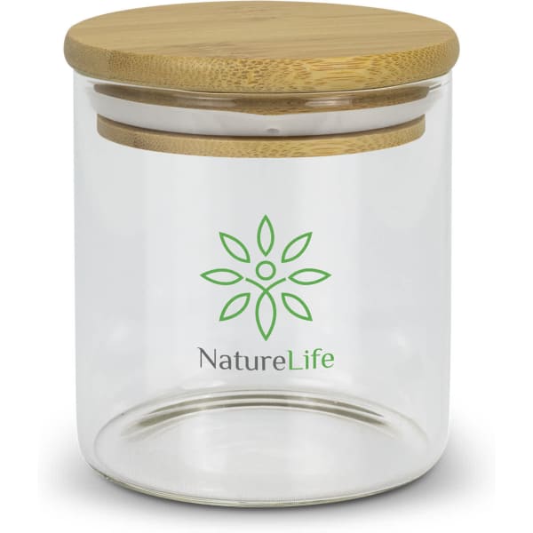 A small round glass storage canister with a bamboo lid and a green logo on the front.