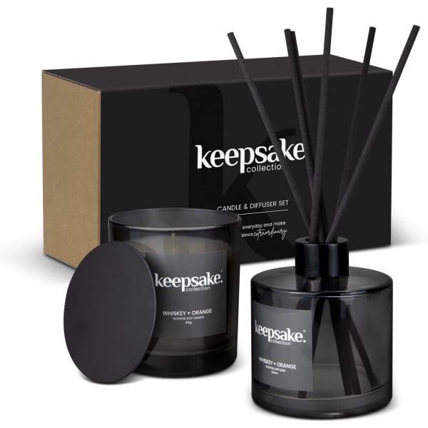 A black candle and diffuser set in a box, featuring whiskey and orange scents, with decorative black reeds.