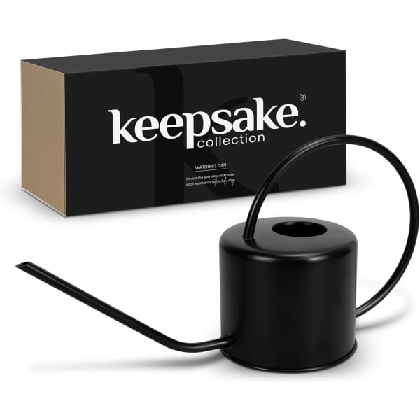 A black watering can with a curved spout, displayed beside its box featuring a logo.