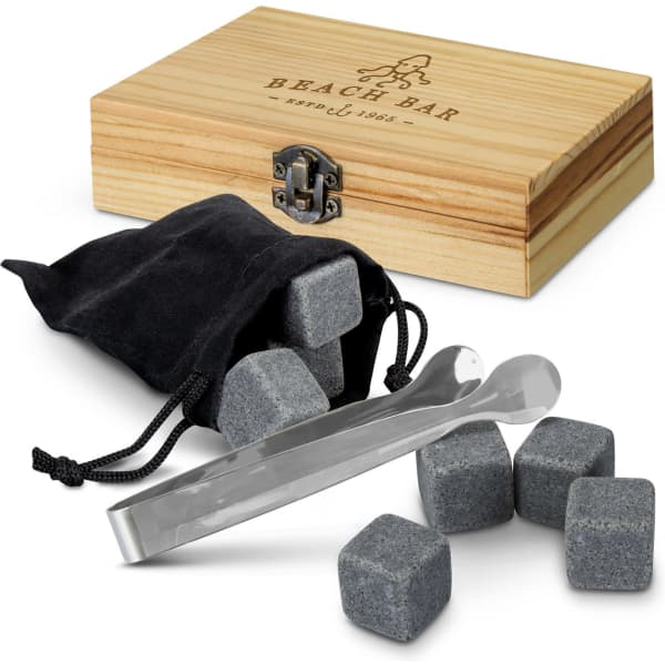 A wooden box contains grey whiskey stones, a black pouch, and stainless steel tongs for chilling drinks.