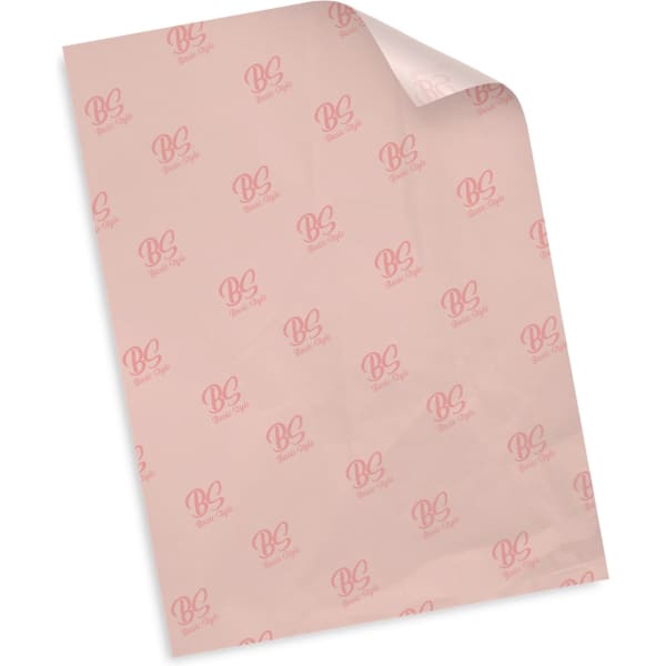 A piece of pale pink tissue paper featuring a repeated logo pattern. The paper is slightly curled at one corner.