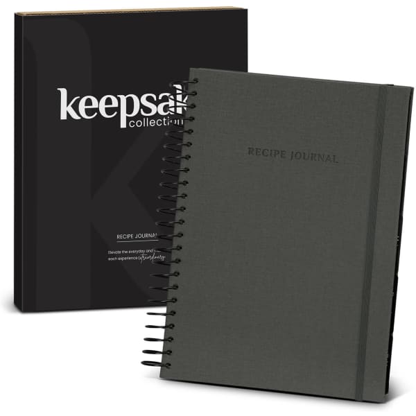 A dark grey spiral-bound recipe journal with a black box featuring a logo.