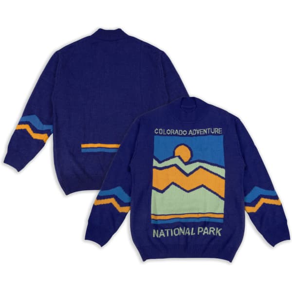 A blue knitted jumper featuring a mountain landscape design in yellow and orange, with a logo on the back.