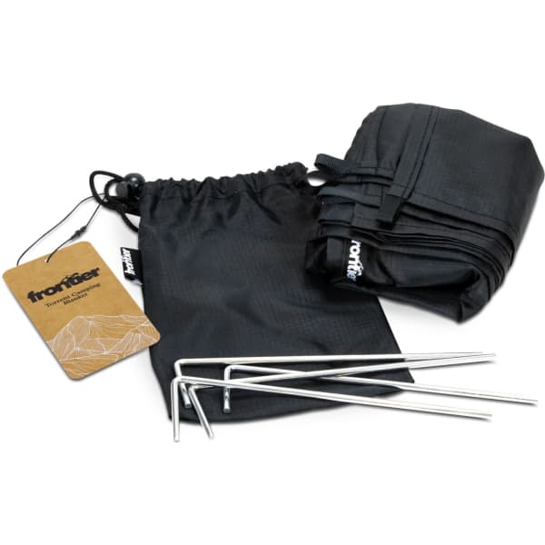 A black camping blanket folded in its storage bag, accompanied by silver pegs and a tag featuring a logo.