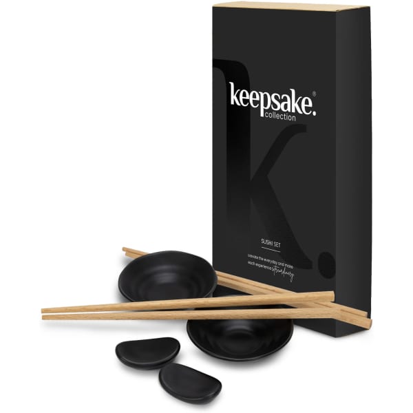 A sushi set featuring black dishes, wooden chopsticks, and packaged in a black box with branding.