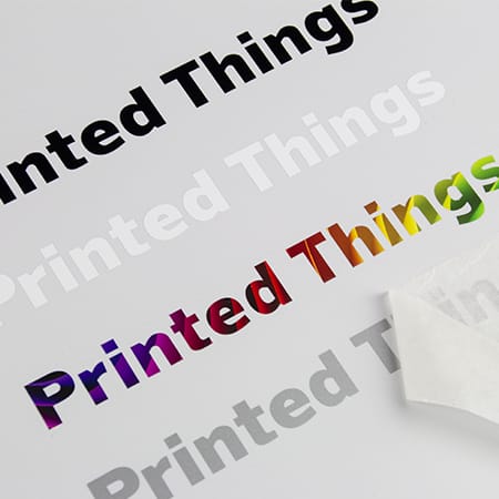 A sheet of tape transfer stickers featuring the text "Printed Things" in black, white, and rainbow colours.