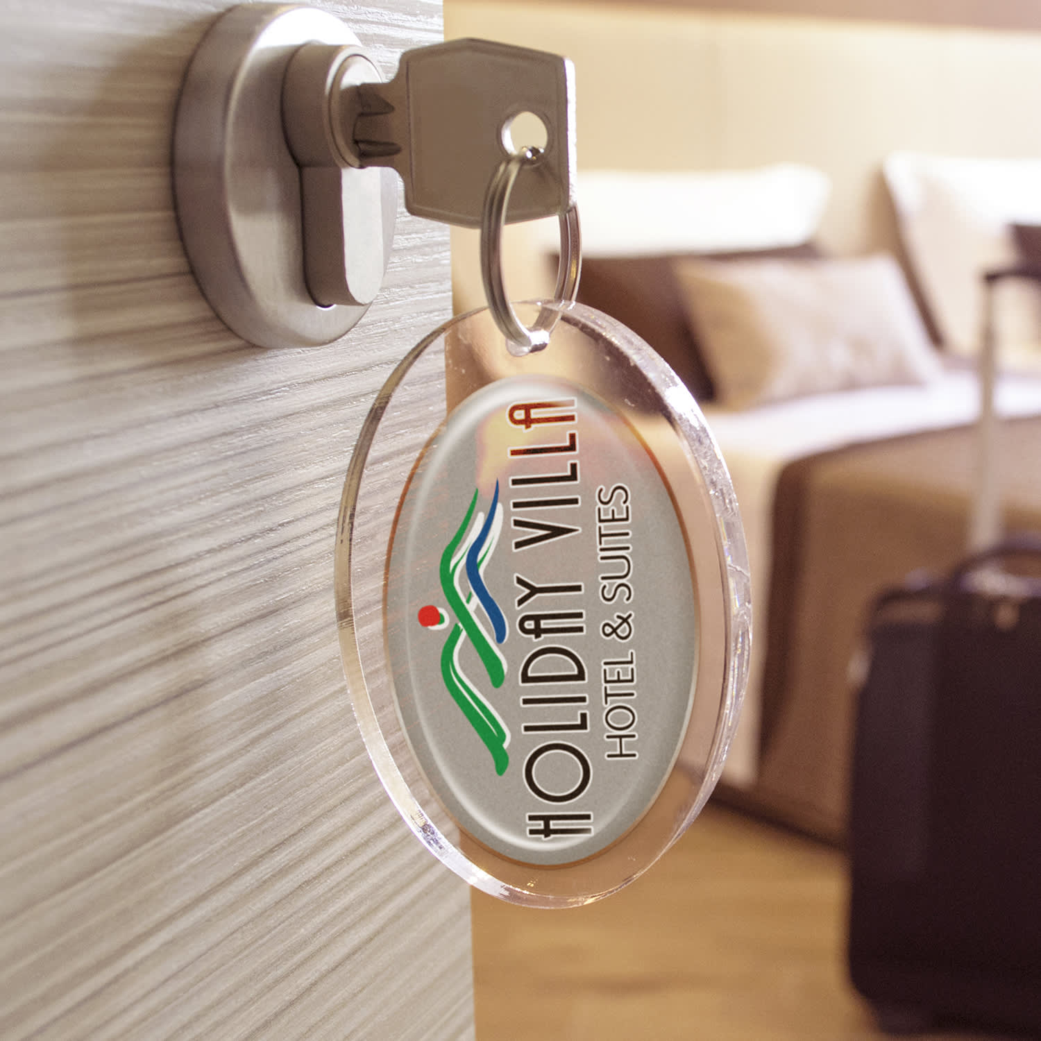 A keychain with an oval resin-coated label featuring the text "HOLIDAY VILLA HOTEL & SUITES" is hanging from a door key.